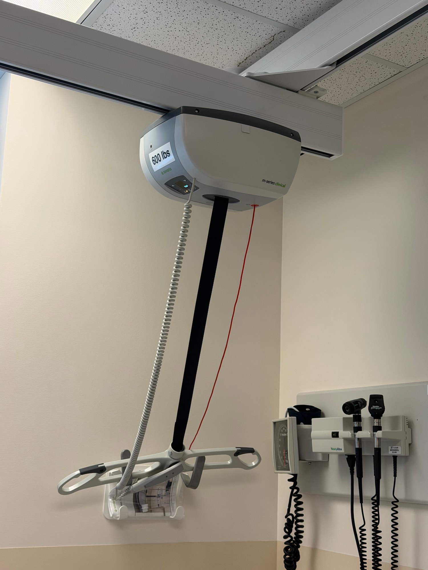 Ceiling patient lift above an exam bed in a clinic room